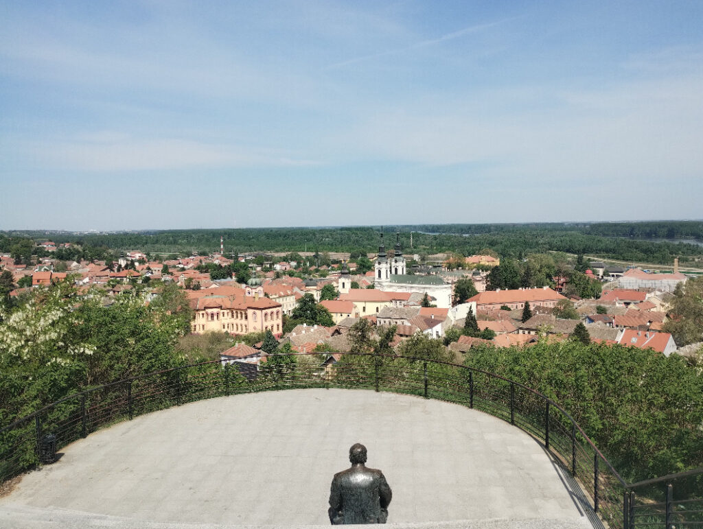 pogled na kameni plato sa statuom i koja je okrenuta na panoramu naseljenog mesta